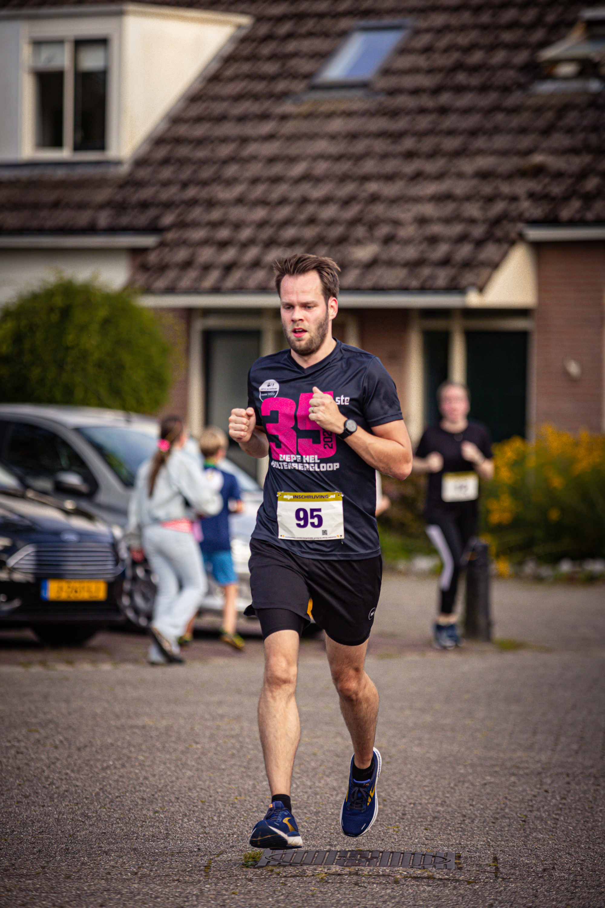 A man running in a residential street with number 95 on his shirt.