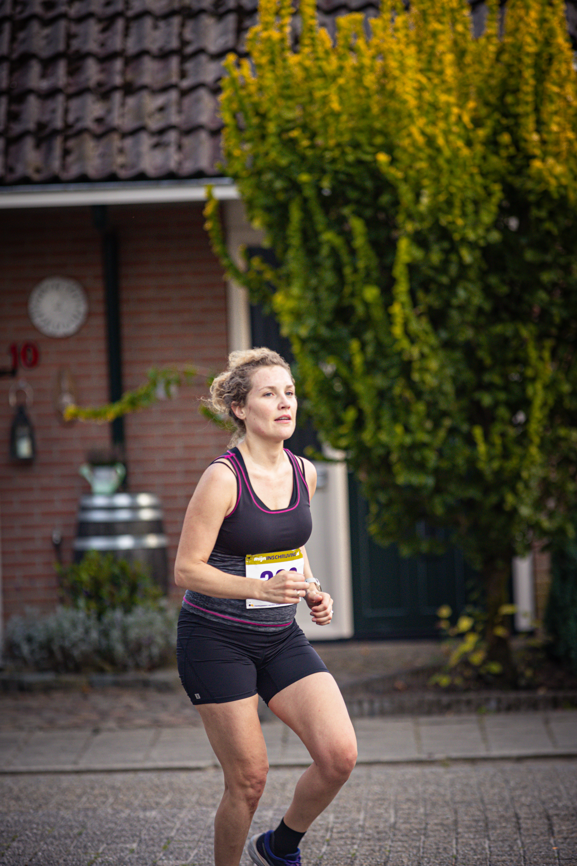 A woman is running outside. She has a name tag on her shirt that reads "Pomplop".