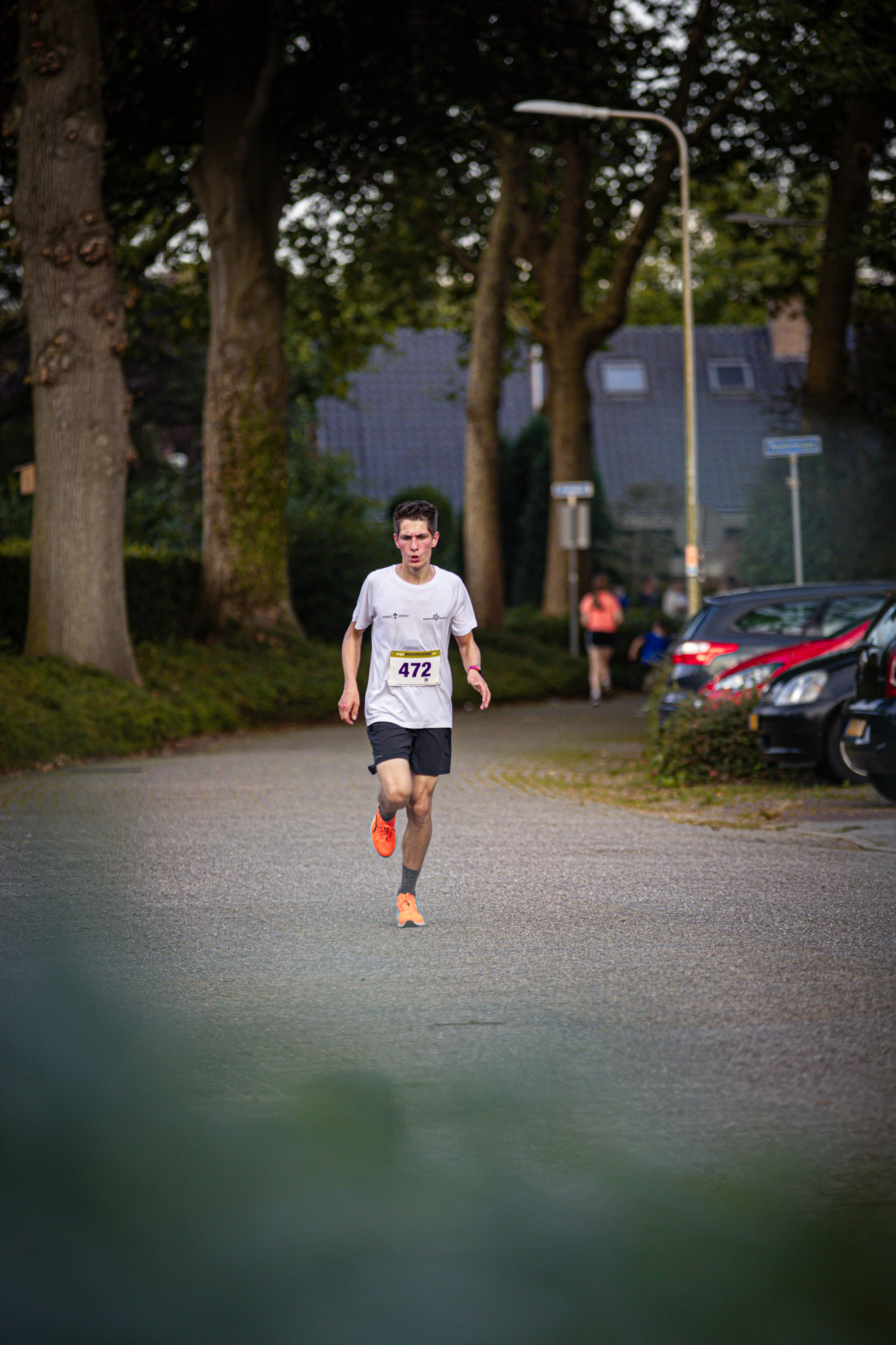 A man wearing a white shirt with 42 on it. He is running through an empty parking lot.