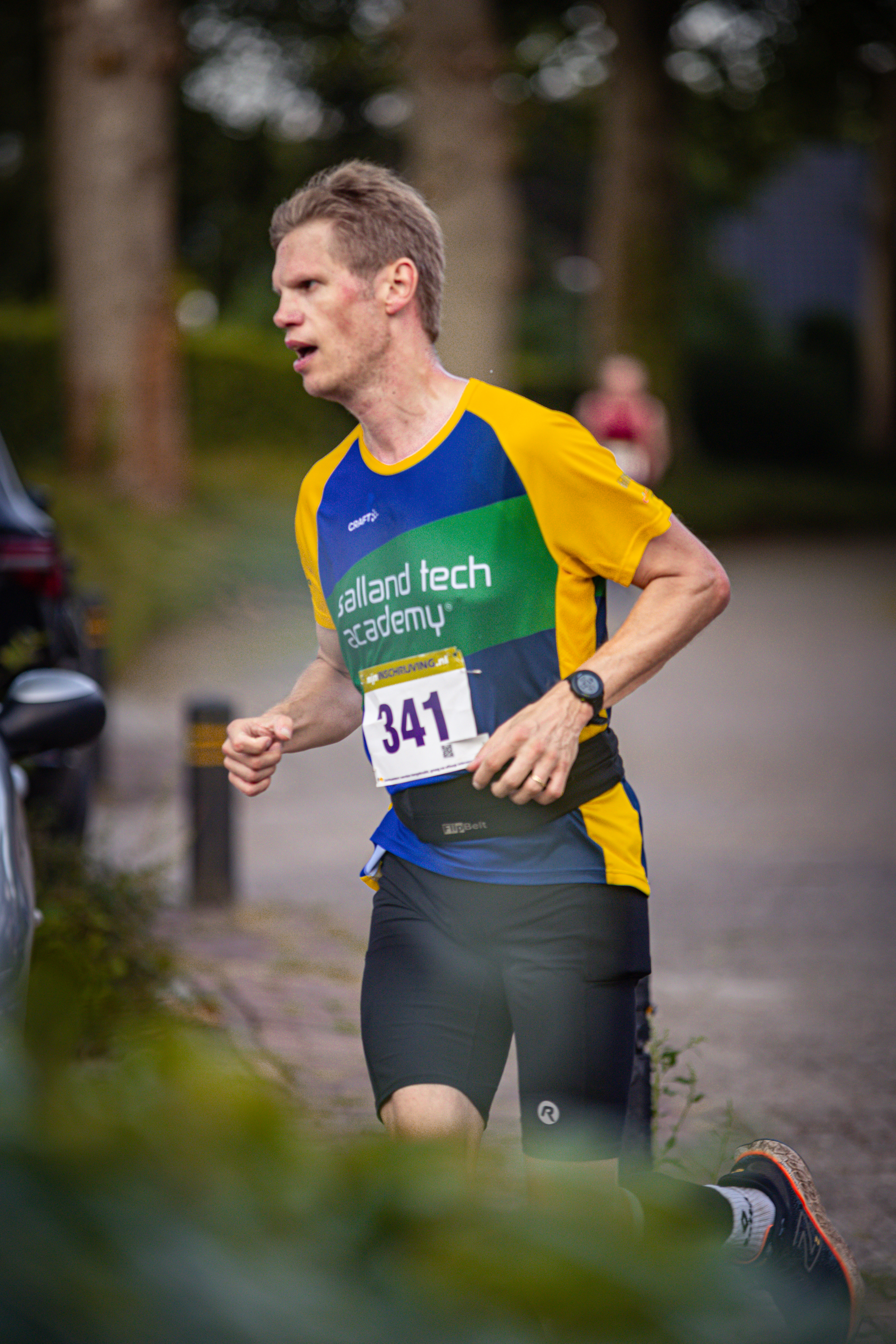 A runner in a yellow and blue shirt is wearing the number 341.