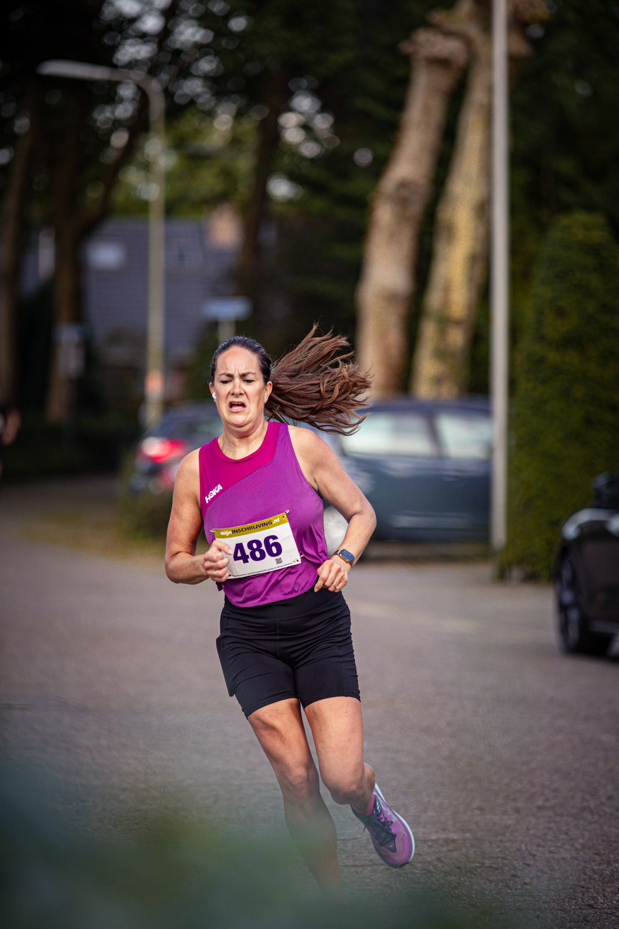 A lady with a pink tank top and the number 488 on her jersey is running.