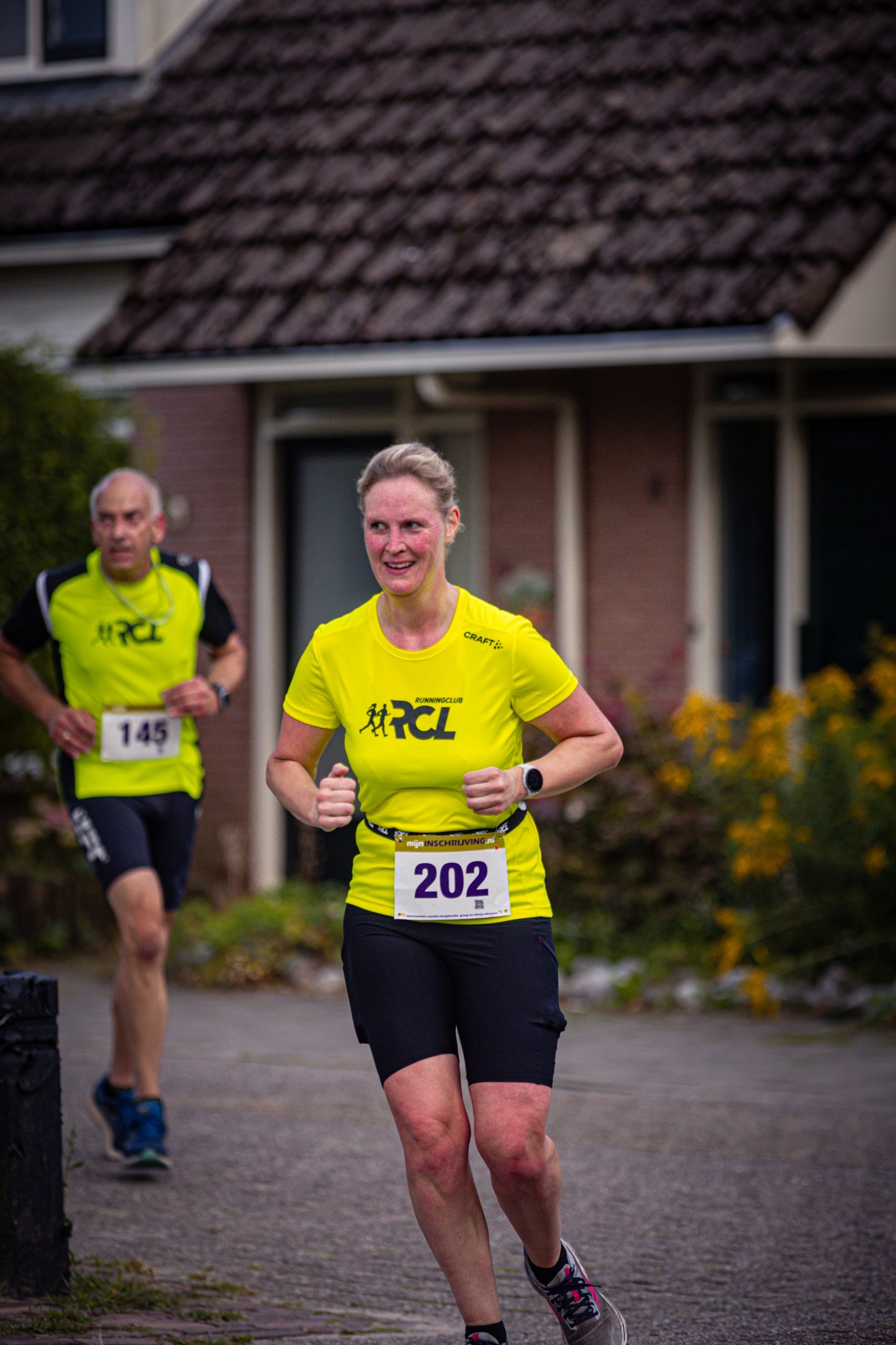 Two runners are participating in a race with a number 14 and a number 202.