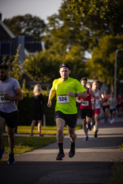 A man runs in a marathon with the number 524 on his bib.