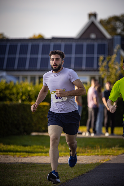 A man in a blue and white shirt running on a street with a number 8 on his chest.