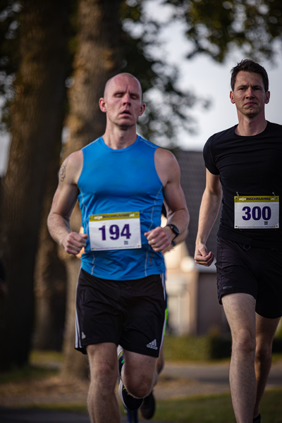 Two men are running in a race with 194 and 300 numbered jerseys.