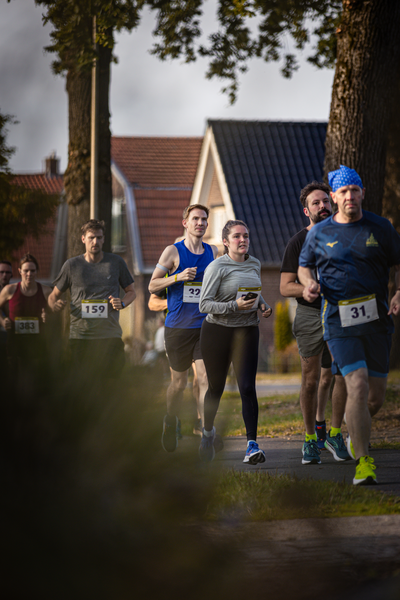 A man and woman running in a race while wearing numbers 23 and 31.