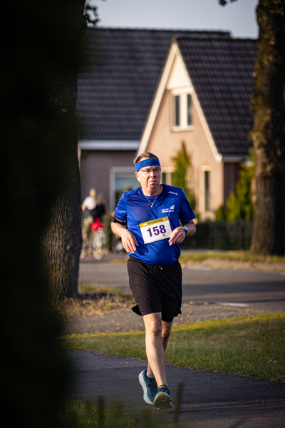 Man running in a blue shirt with the number 158 on it.