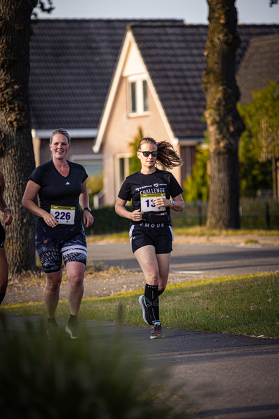 Two women running in a park with numbers 210 and 13.