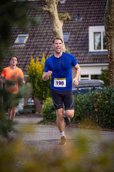 A man running with the number 199 on his shirt and blue shorts. He is wearing a yellow bib.