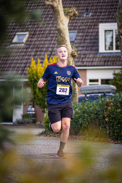 A man wearing a 228 race bib runs through a neighborhood.