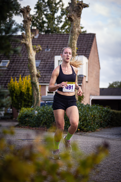 A girl running on a street with the number 961 on her jersey.