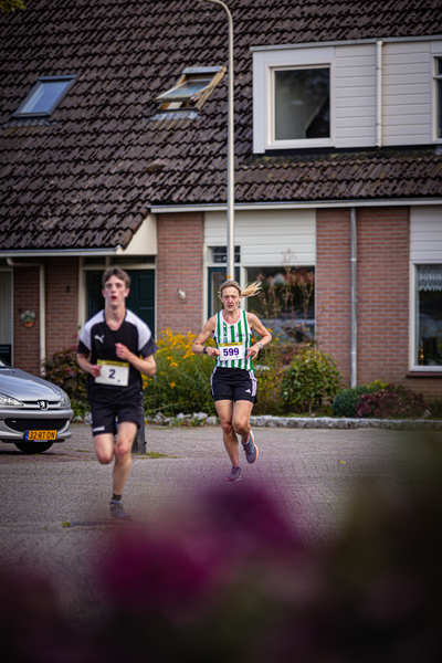 A woman in a striped shirt is running in a race, and another runner is on her right.