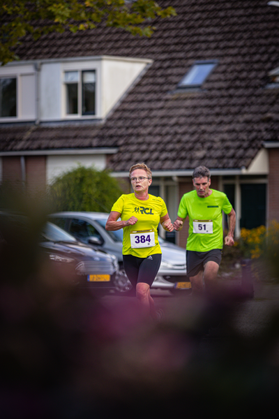 Two men running in a race. One is wearing the number 38 and the other 81. They are running together down the street.