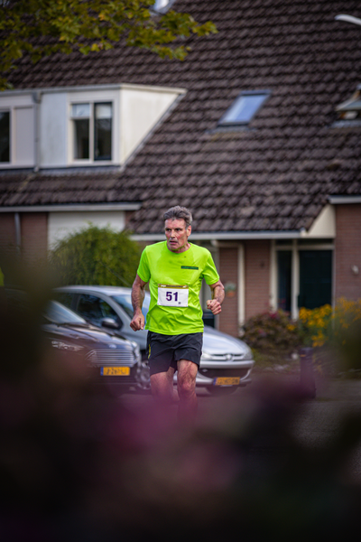 A man running in the street wearing a green shirt with number 51 on it.