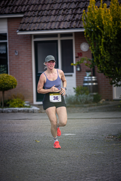 A woman running on a city street with the number 36 pinned to her shirt.