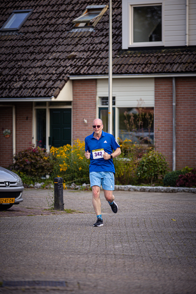 A man running in a blue shirt and shorts with the number 24 on his back.