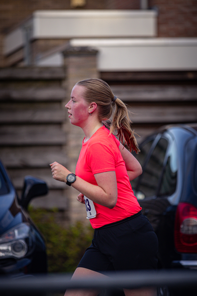 A woman is running on a road with the number 3 on her shirt.