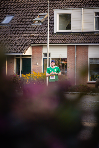 A man in a green jersey with the number 34 on it stands in front of a brick building.