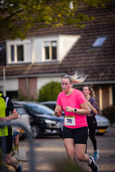 A woman in a pink shirt running with the number 70 on her chest.