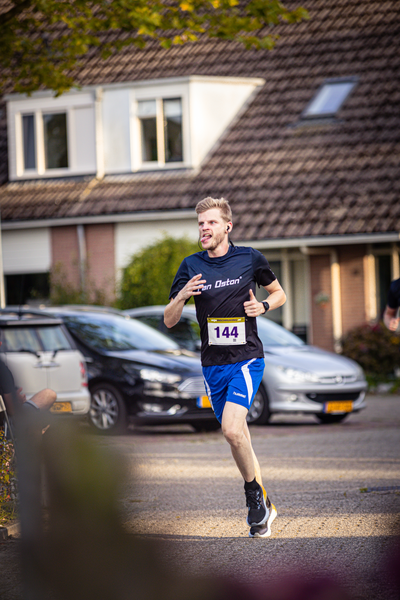 A man in a blue shirt with 214 on it running down the street.