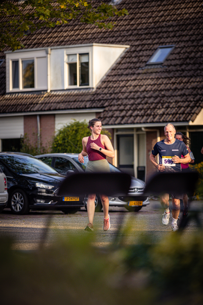 A couple running together while a person walks on the street.