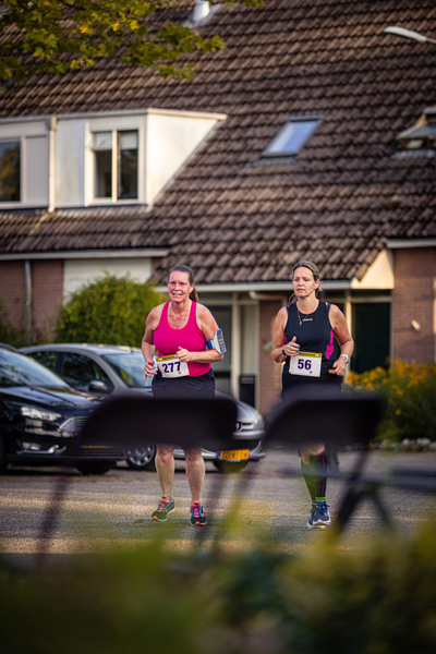 Two women are running in a race. They have bibs with the numbers 35 and 38 on them.