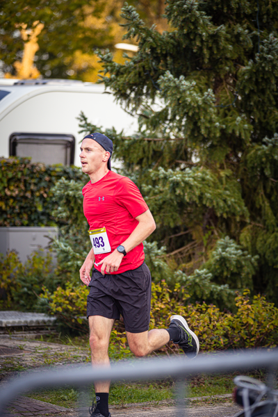 A man in a red shirt and shorts runs down the street.