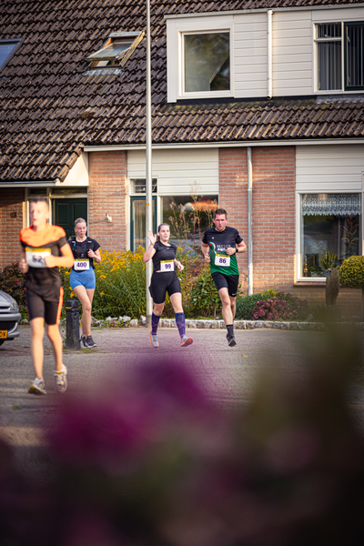 A group of runners are participating in a race near a house.