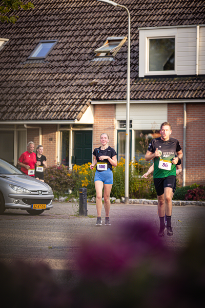 Two runners on a road with one in a green shirt and the other in black.