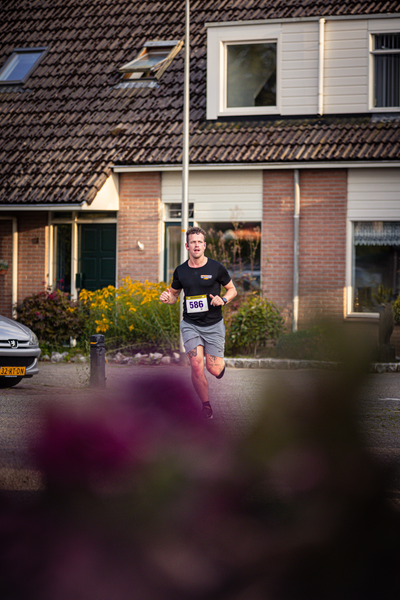 A man running in front of a building with the number 58 on his shirt.