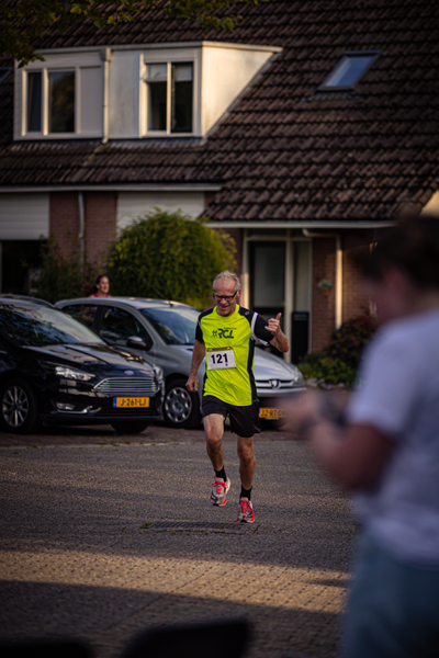 A man runs down a street wearing a yellow Pomploot shirt with the number 1 on it.