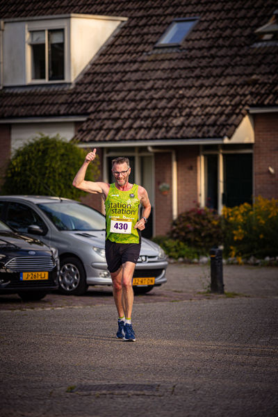 The runner in the green jersey is about to cross the finish line.