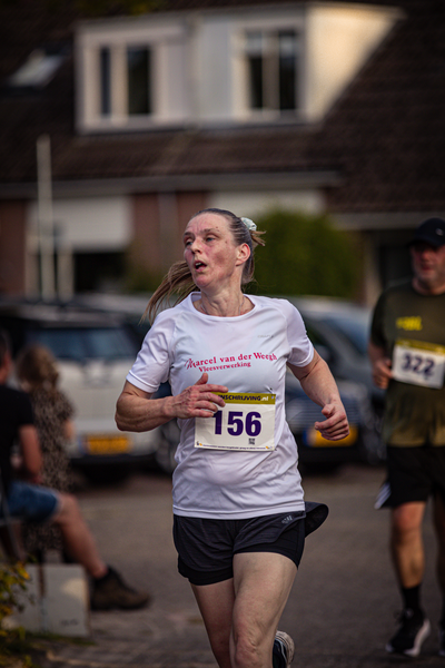 A woman running a race with the number 156 on her shirt.