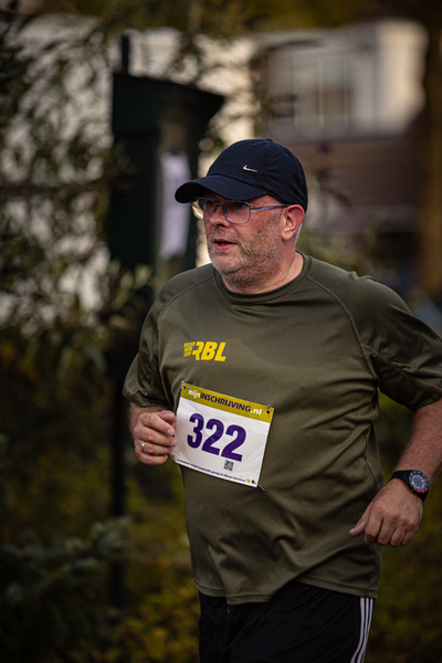 A runner with the number 322 is wearing a black hat and shirt.