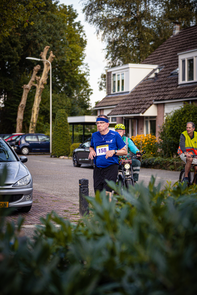 Two people on bicycles in front of a house, one wearing a blue shirt and the other a yellow shirt.