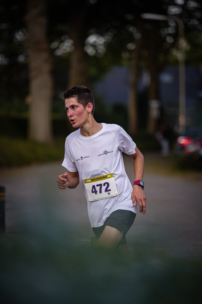 A man in a white shirt with the number 421 on it is running down the road.