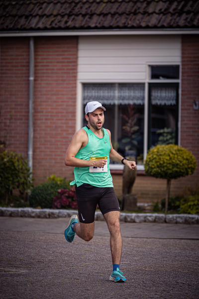 A man in a green shirt and shorts runs across the street, with an air of determination.