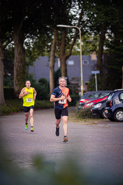 A man running in a marathon while wearing a bib with the number 26 on it.