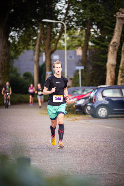 A young man running on a road with 384 written on his shirt.