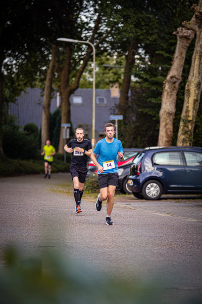 A pair of runners go by a car in what could be a race.