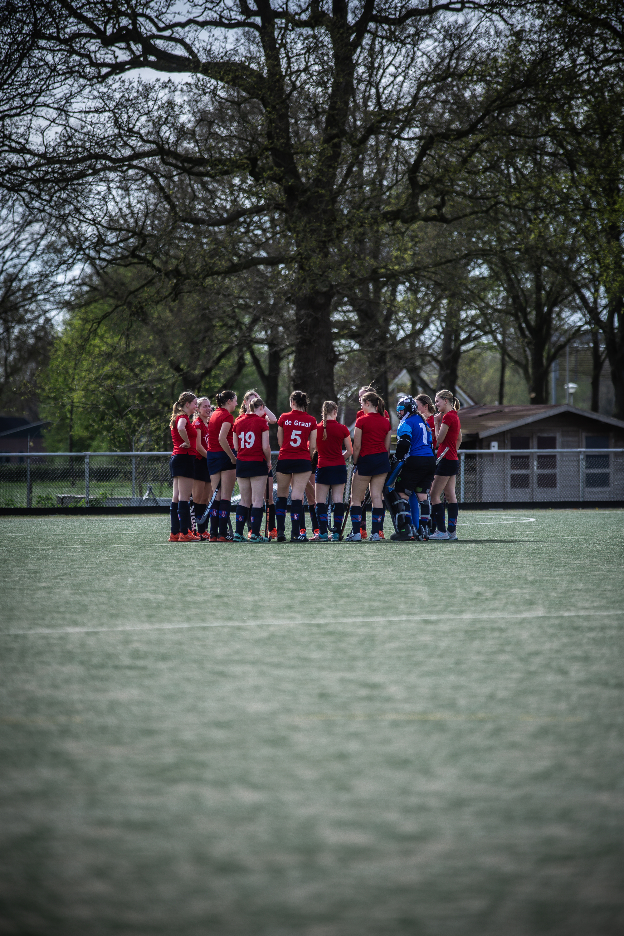 A hockey team with red jerseys is posing on a field.