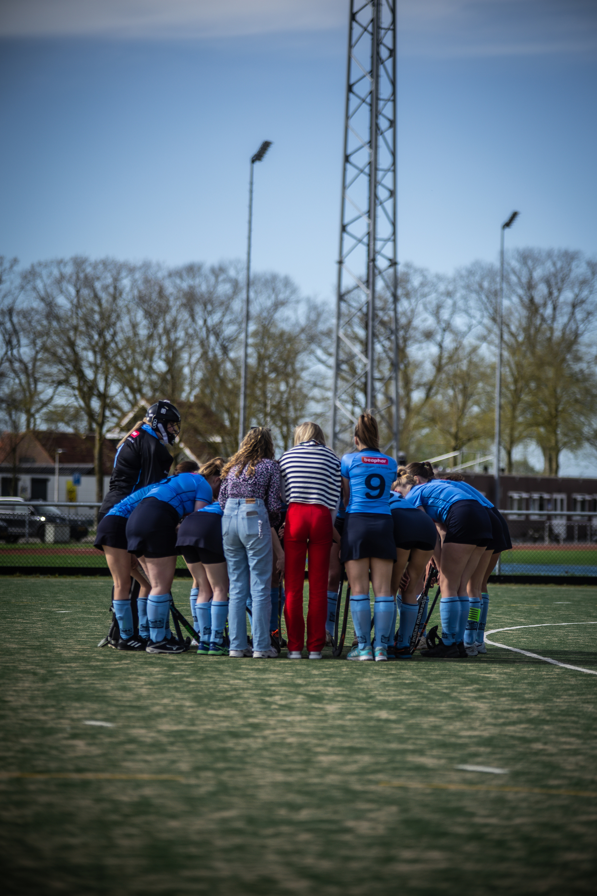 A group of hockey players from SMHC on a field. They are wearing uniforms and huddling up together in unity.