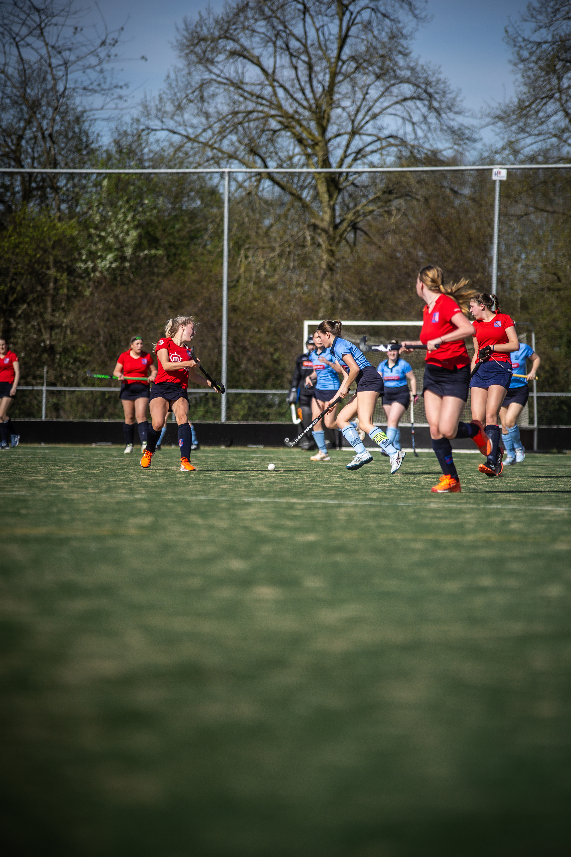 A group of women playing field hockey, one of whom is wearing a number 3 jersey.