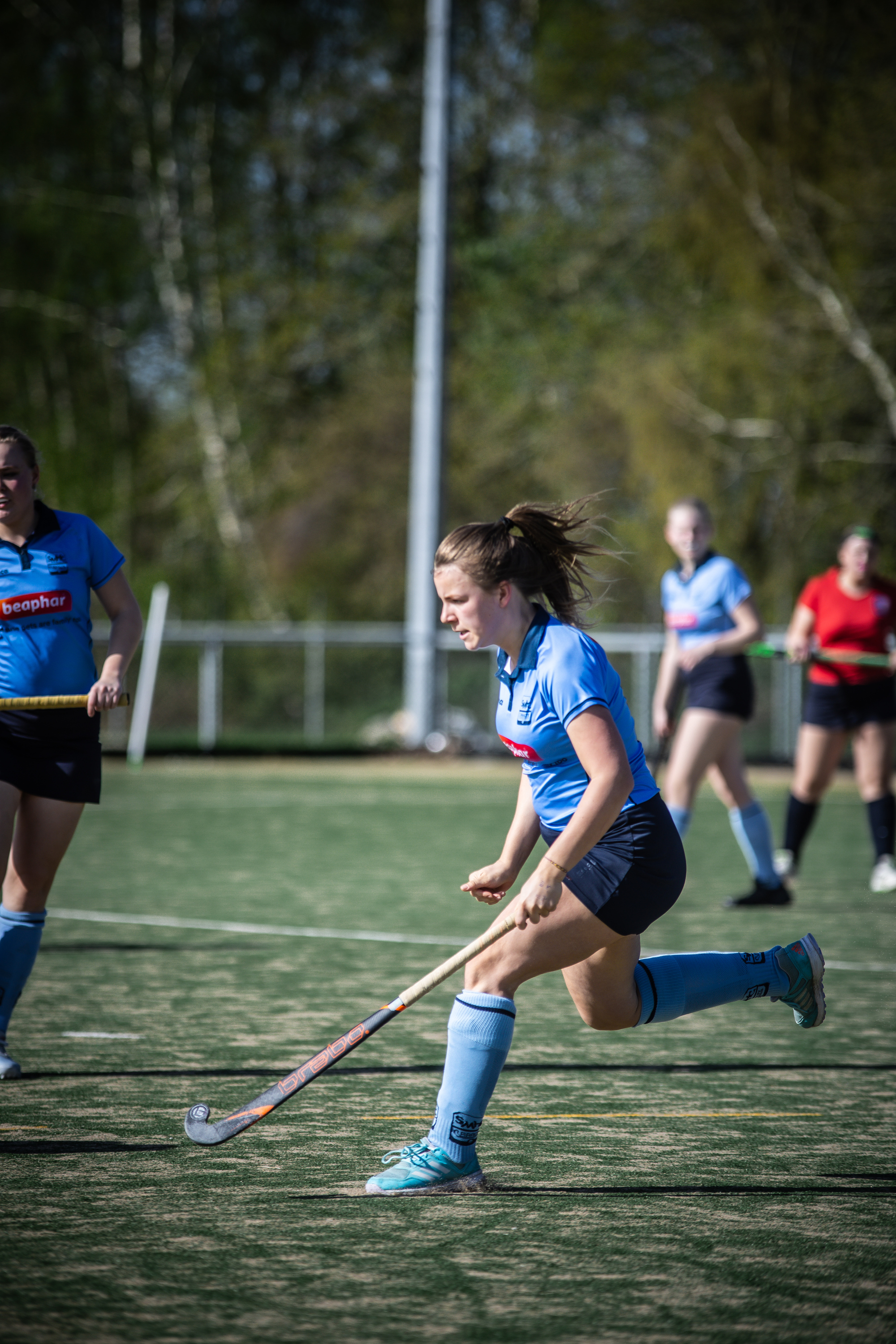 An athlete in a blue uniform is chasing after the puck during a hockey game.