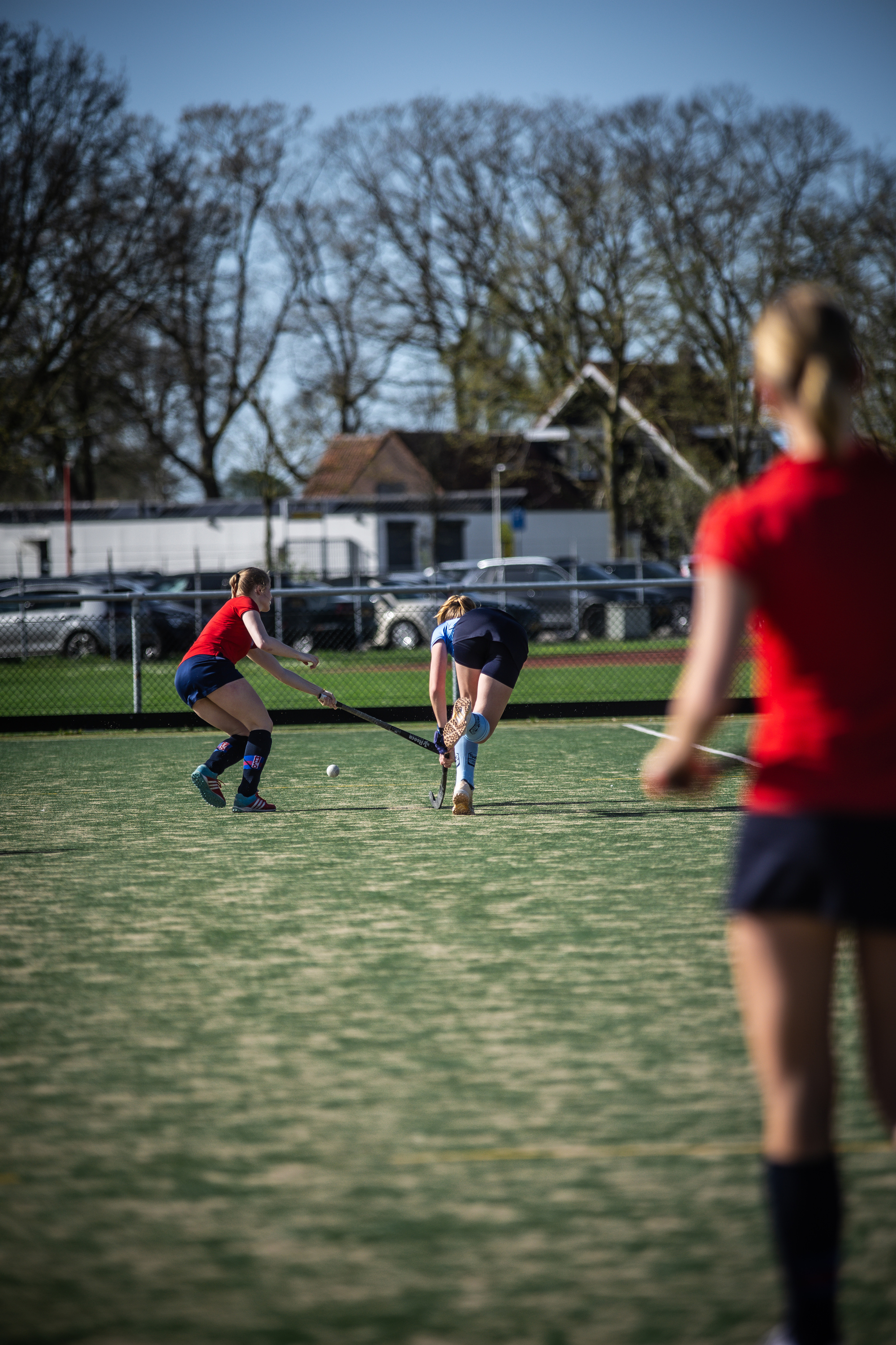 A woman playing hockey on a field, in the background there is another woman.