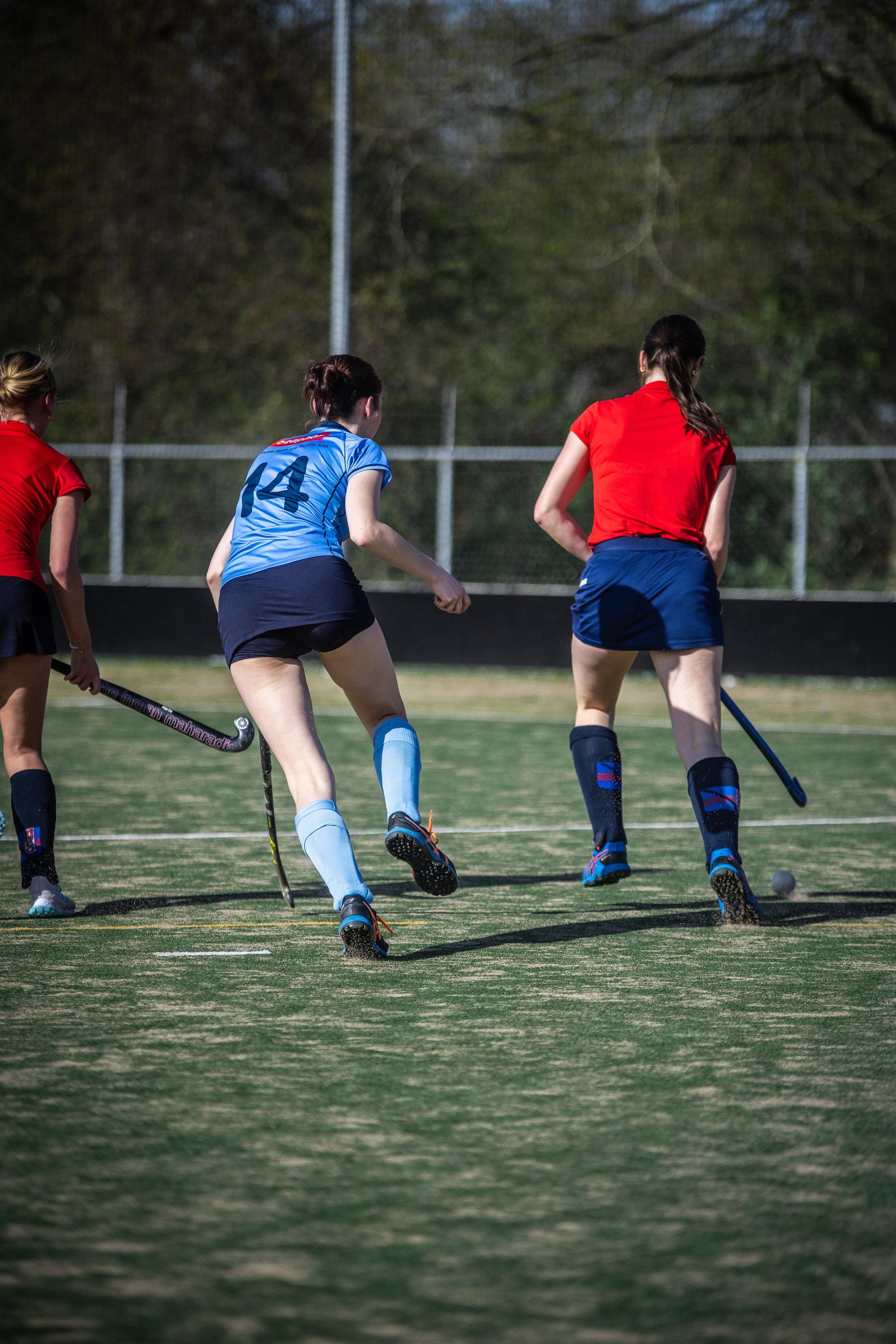 A girl with the number 41 is playing hockey, as she runs along the field with her teammates.