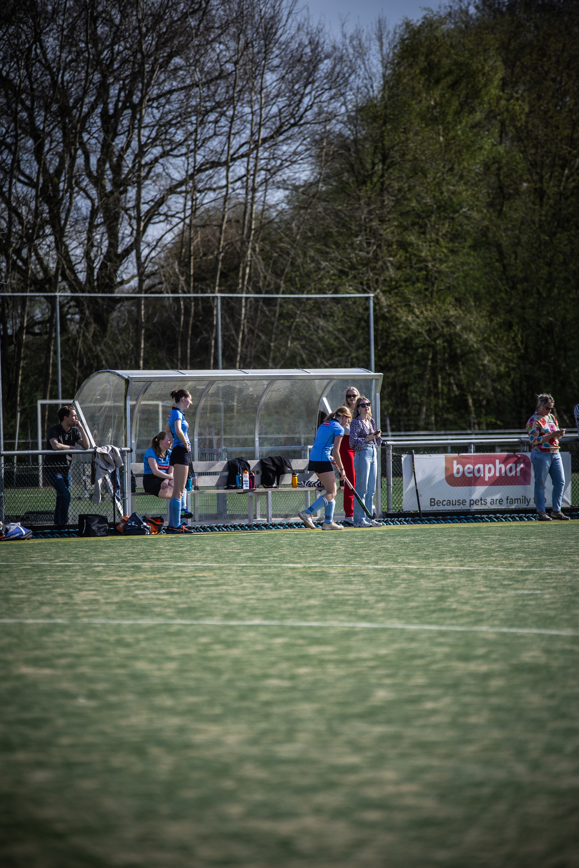 A group of people standing around a hockey game taking place on 7th April.