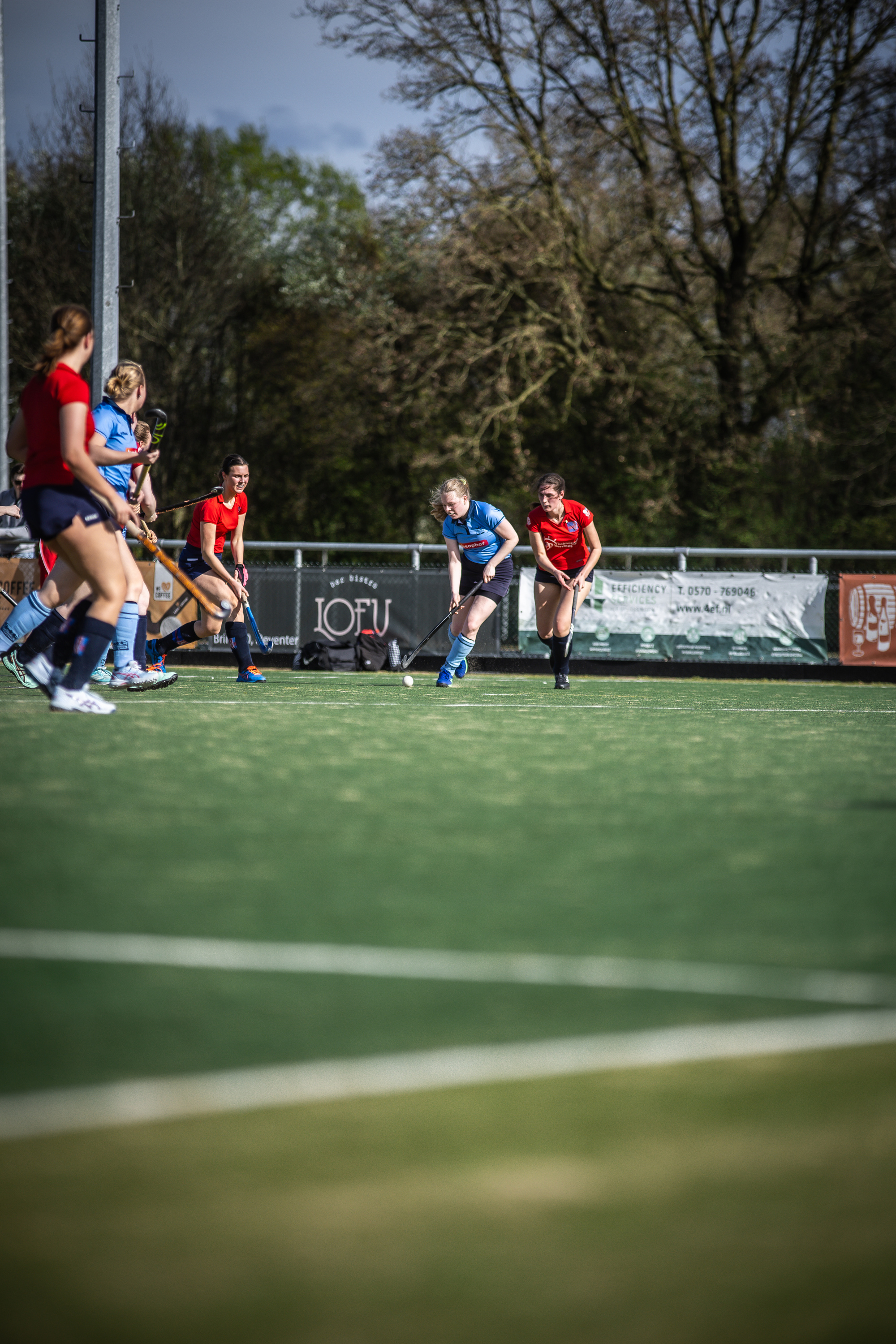 A group of women are playing a game of field hockey on a sunny day in 2024.