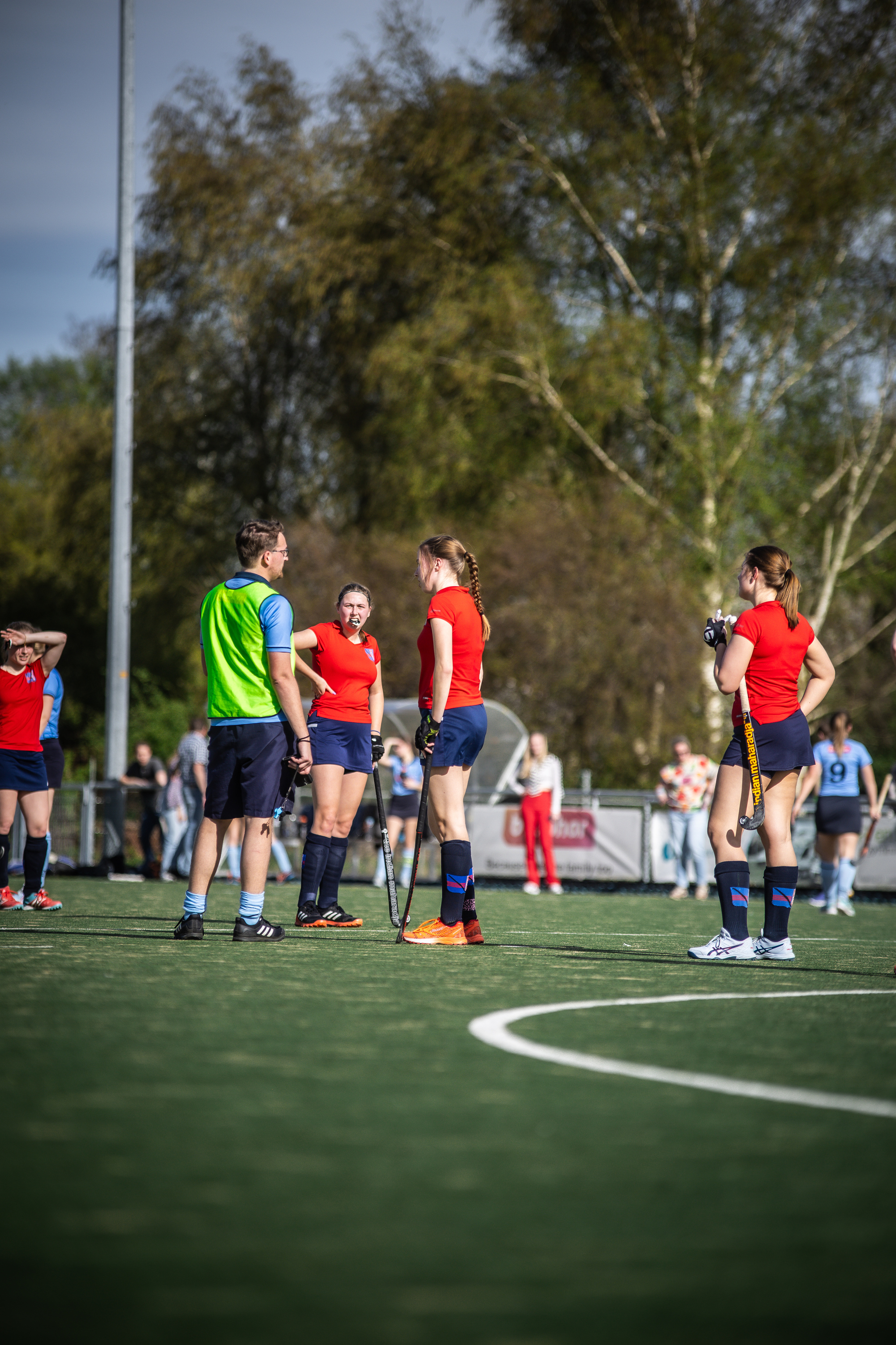 A group of female hockey players standing on a green field with the SMHC logo in the background.