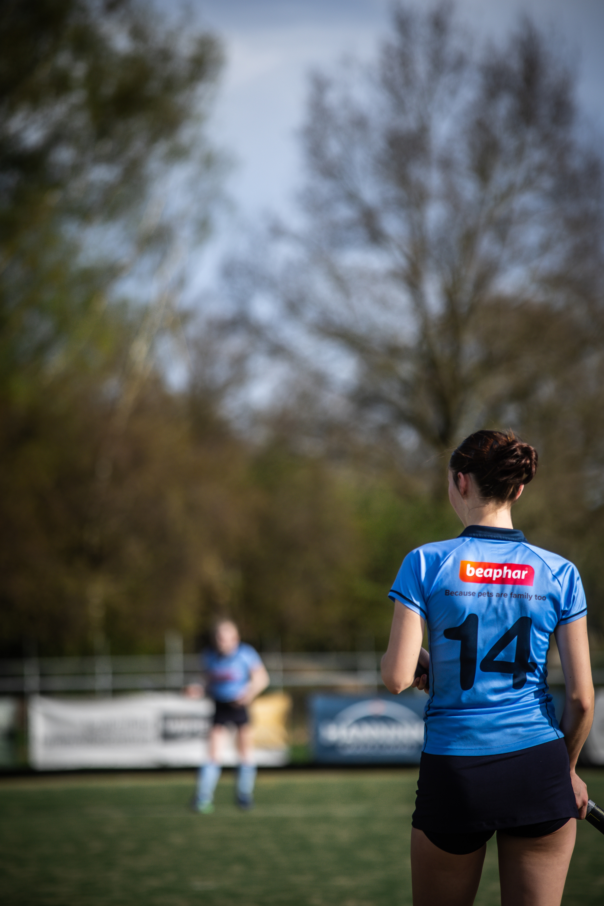 A hockey player wearing blue with 14 on the back stands in front of a sign that says "7 April SMHC".